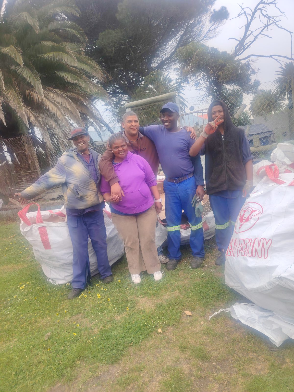 The recycling team standing together beside collection bags